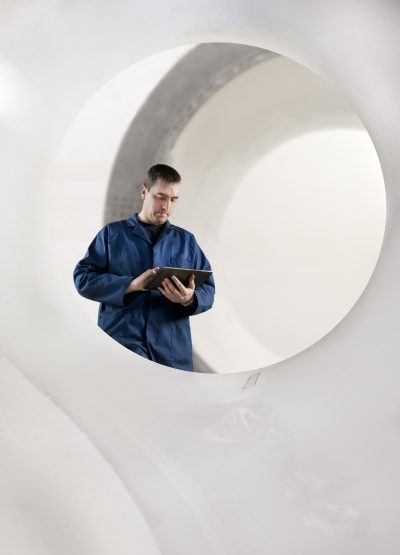 Aerospace technician inspecting airplane shell reactor. Using tablet